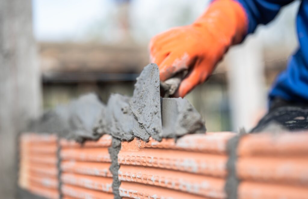 Hand worker masonry brickwork trowel construction site wall concrete background
